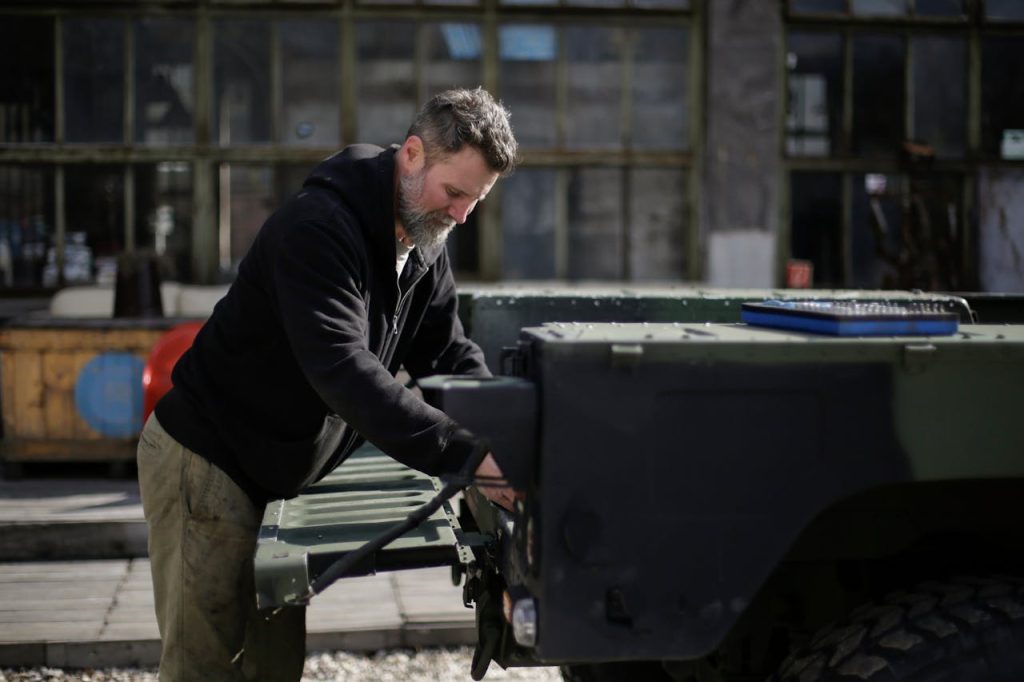 Mechanic performing vehicle inspection in outdoor workshop area.